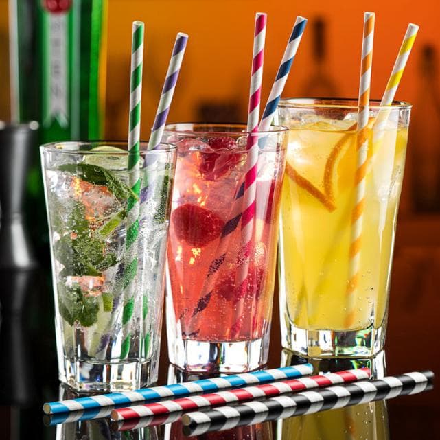 Colorful biodegradable paper straws arranged beside refreshing beverages.